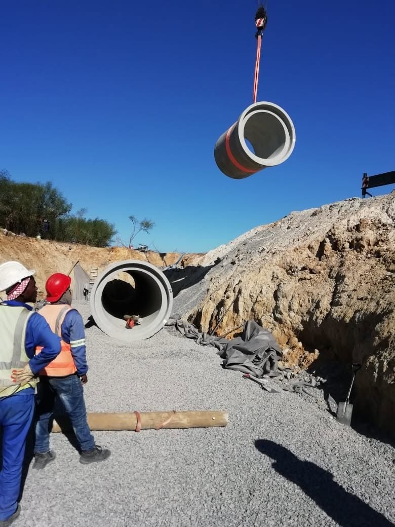 The site team guiding a concrete pipe section into place