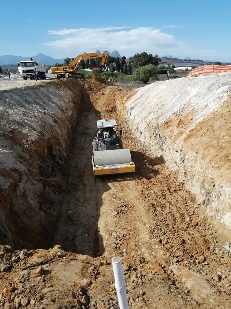 A roller compacting the floor of a deep trench